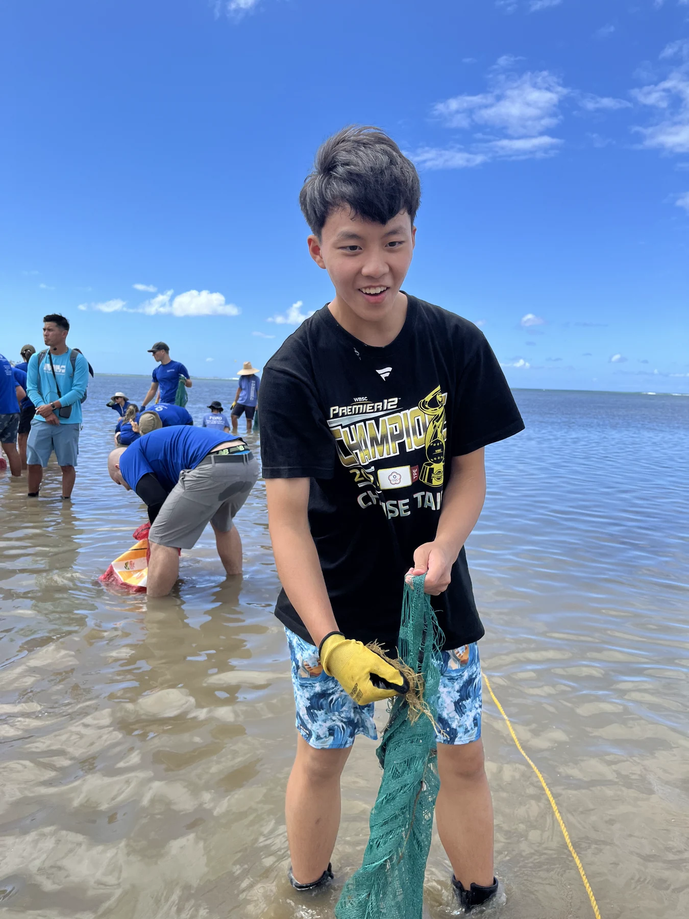 Benjamin holding collected algae while standing in shallow coastal water