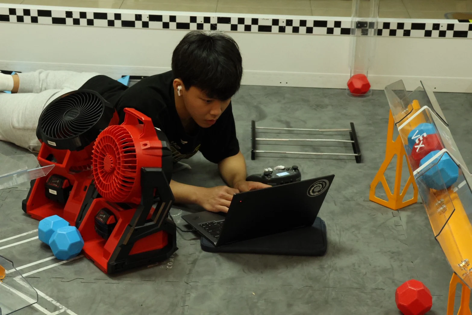 Benjamin programming on a laptop beside the VEX game field